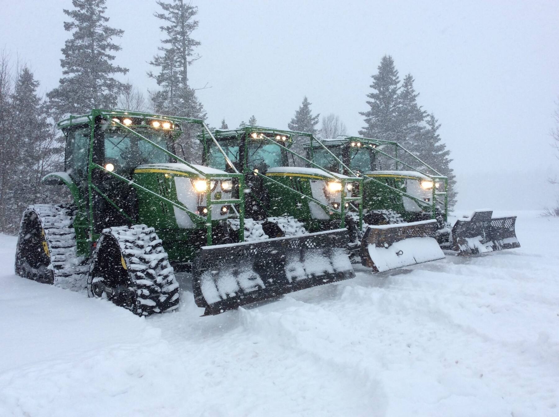 Three PEISA tracked groomers lined up in falling snow